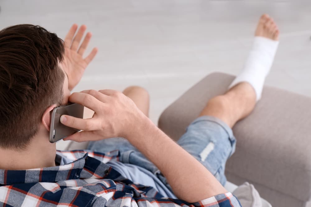 male employee with foot injury on phone reporting his workers compensation claim
