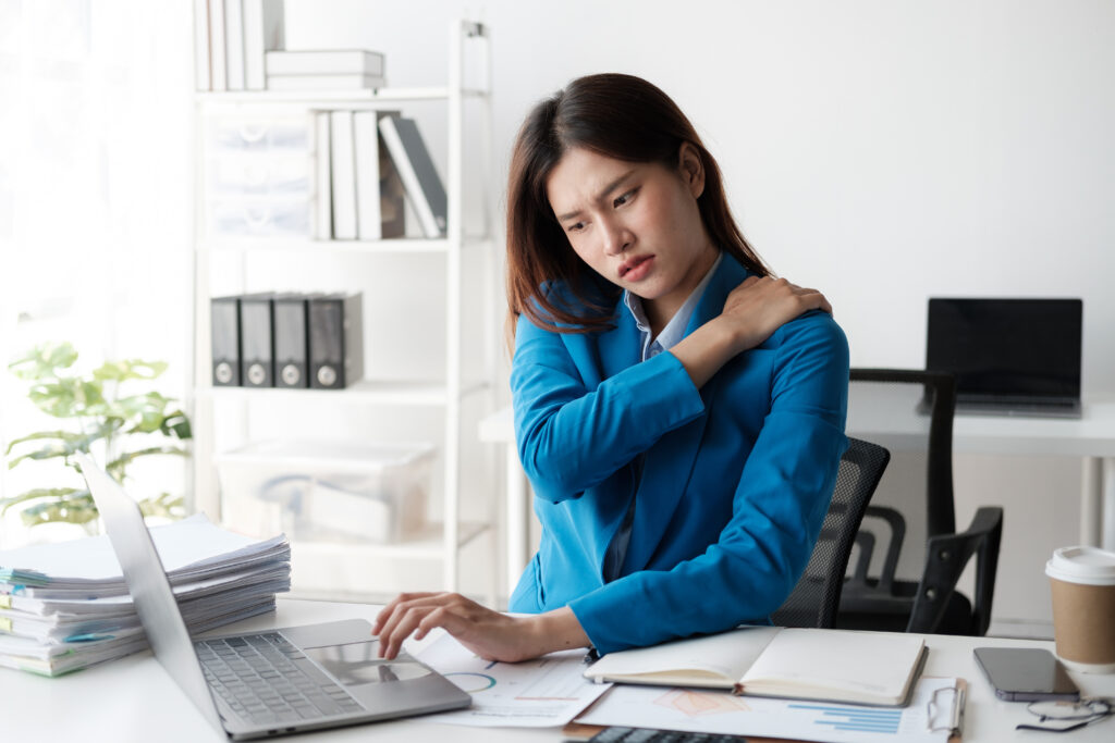 businesswoman at work with shoulder pain while doing desk job